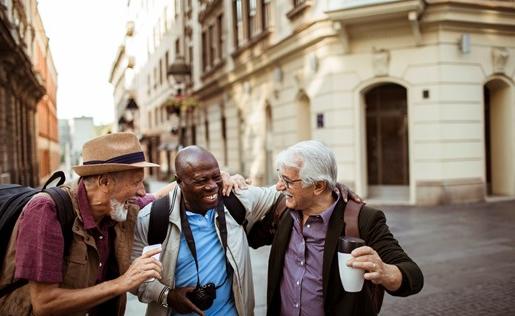 Three older gentleman laughing walking through an old town.