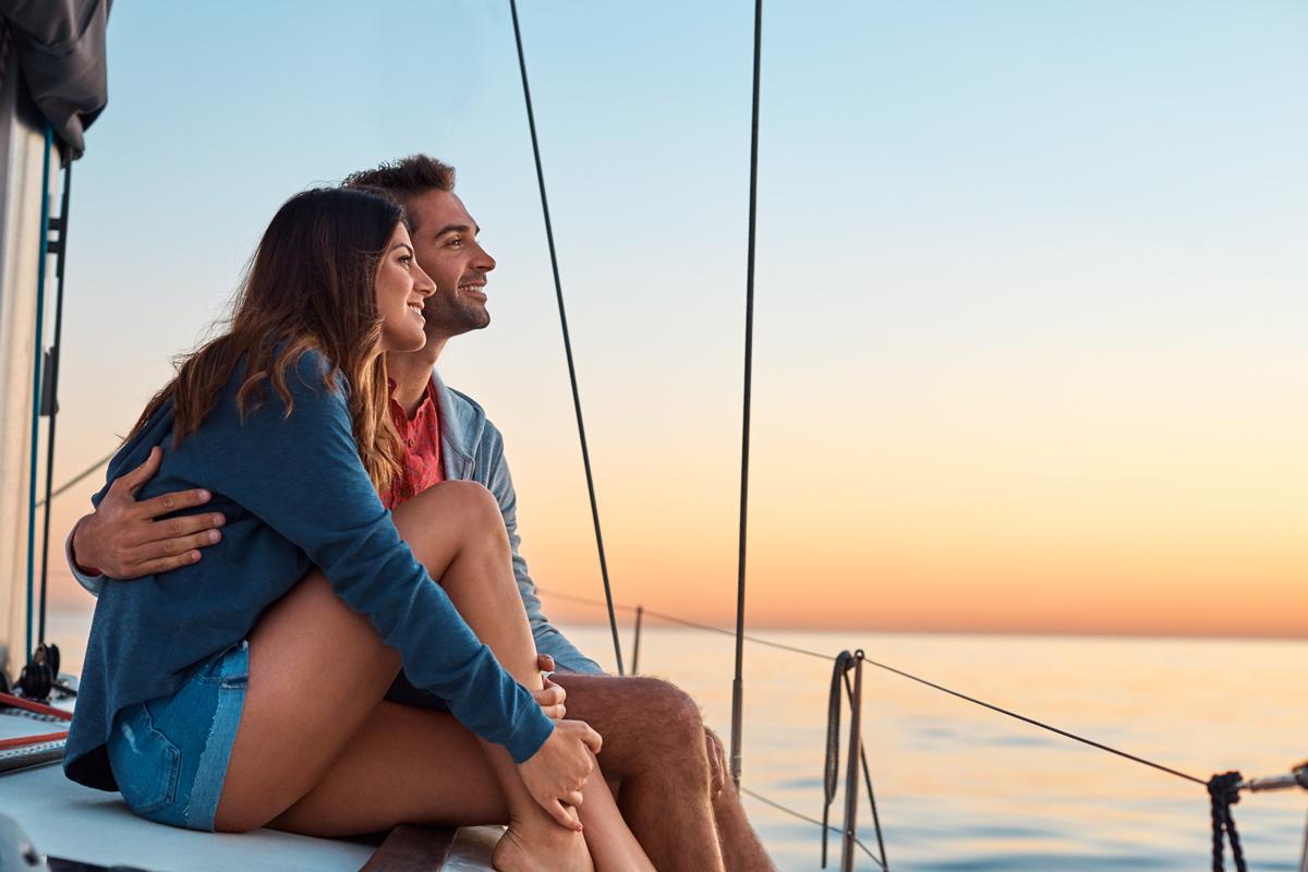 情侣拥抱，在帆船上看日落.